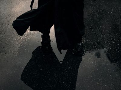 A person's feet standing firmly on a dark surface.